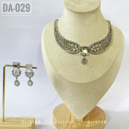 Silver-tone openwork necklace with a central drop and matching earrings on a display bust