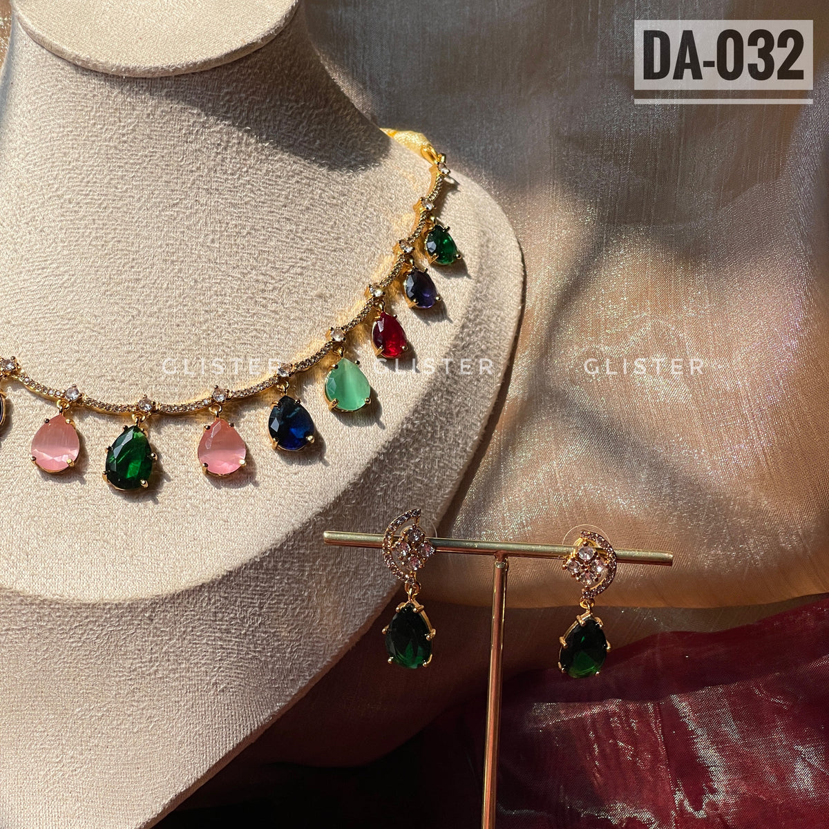 Gold-tone necklace with multicolor teardrop accents and matching green earrings on a display bust