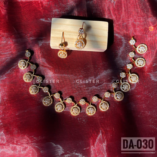 Gold-tone necklace and earrings with round clear-accent motifs laid on red fabric