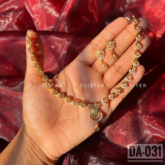 Gold-tone necklace with a teardrop pendant and matching earrings held in a hand
