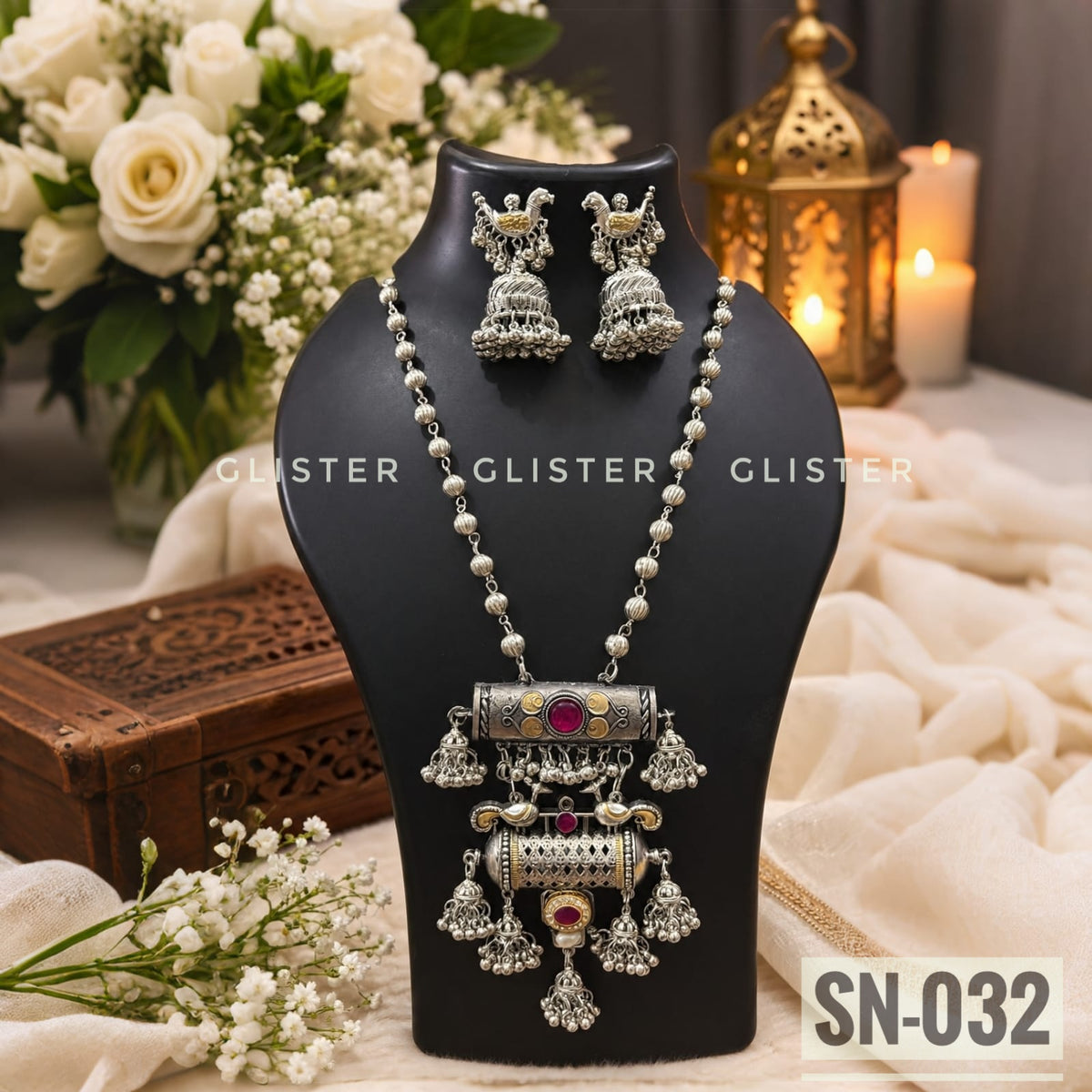 Silver-tone necklace with a layered pendant and matching jhumka earrings on a black bust