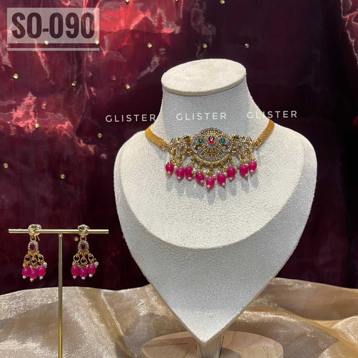 Gold-tone choker set with magenta bead drops on a display bust