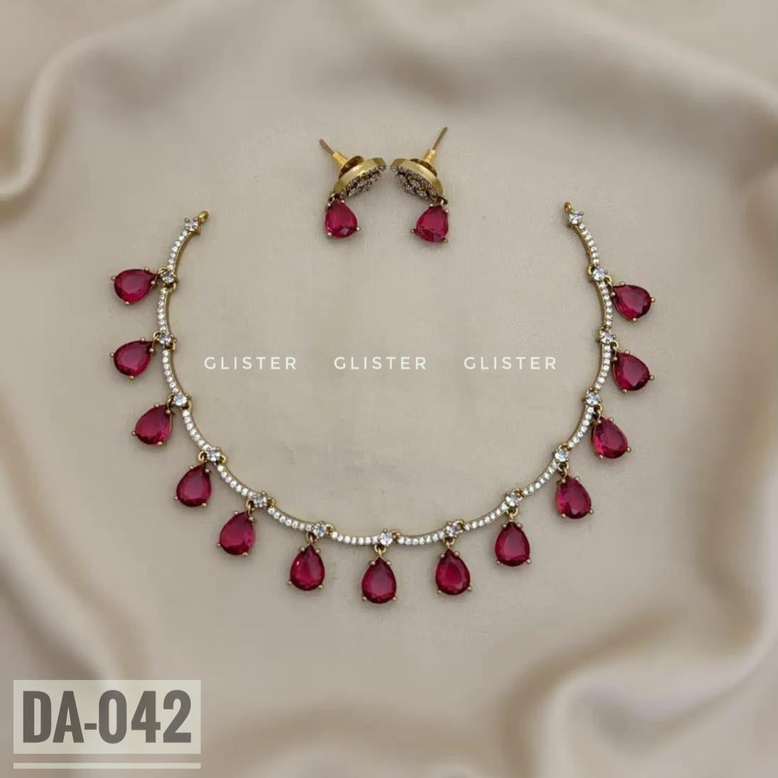 Silver-tone necklace with magenta teardrop accents and matching earrings on pale fabric