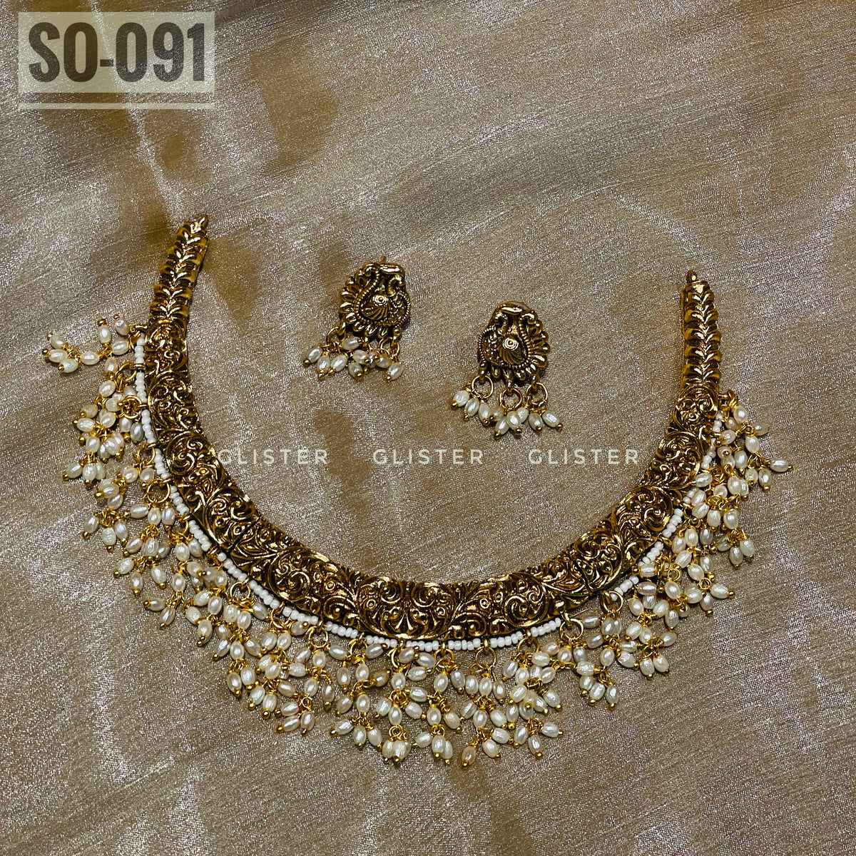 Gold-tone choker and earrings with white bead drops laid on fabric