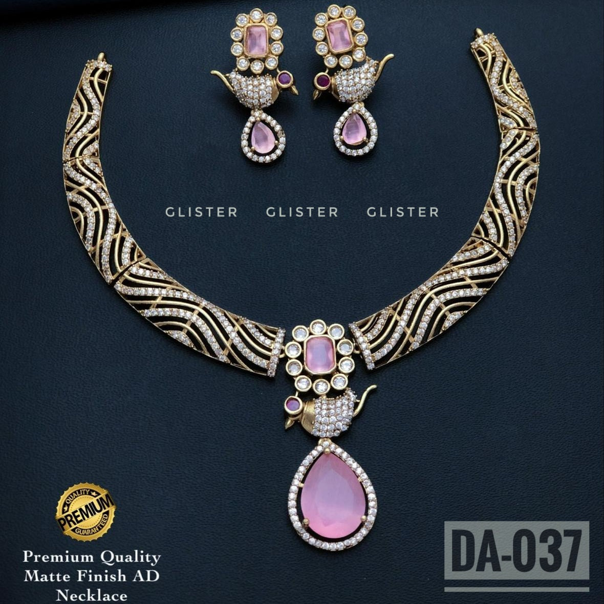 Gold-tone patterned necklace with a lavender teardrop pendant and matching earrings on a dark background