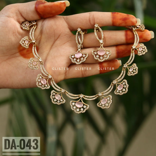 Gold-tone necklace with pink floral drops and matching earrings held in a hand