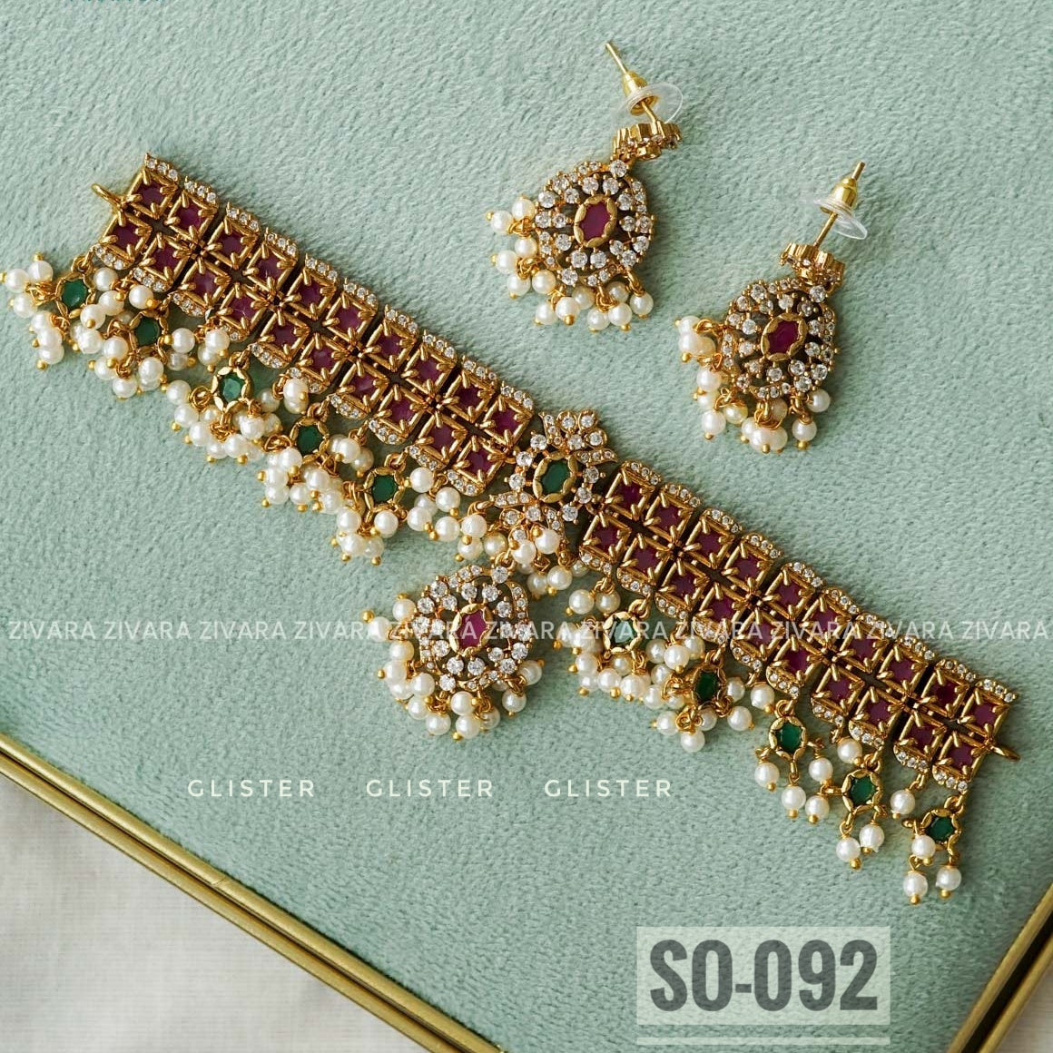 Gold-tone geometric choker with magenta accents, bead fringe, earrings and a forehead ornament on fabric