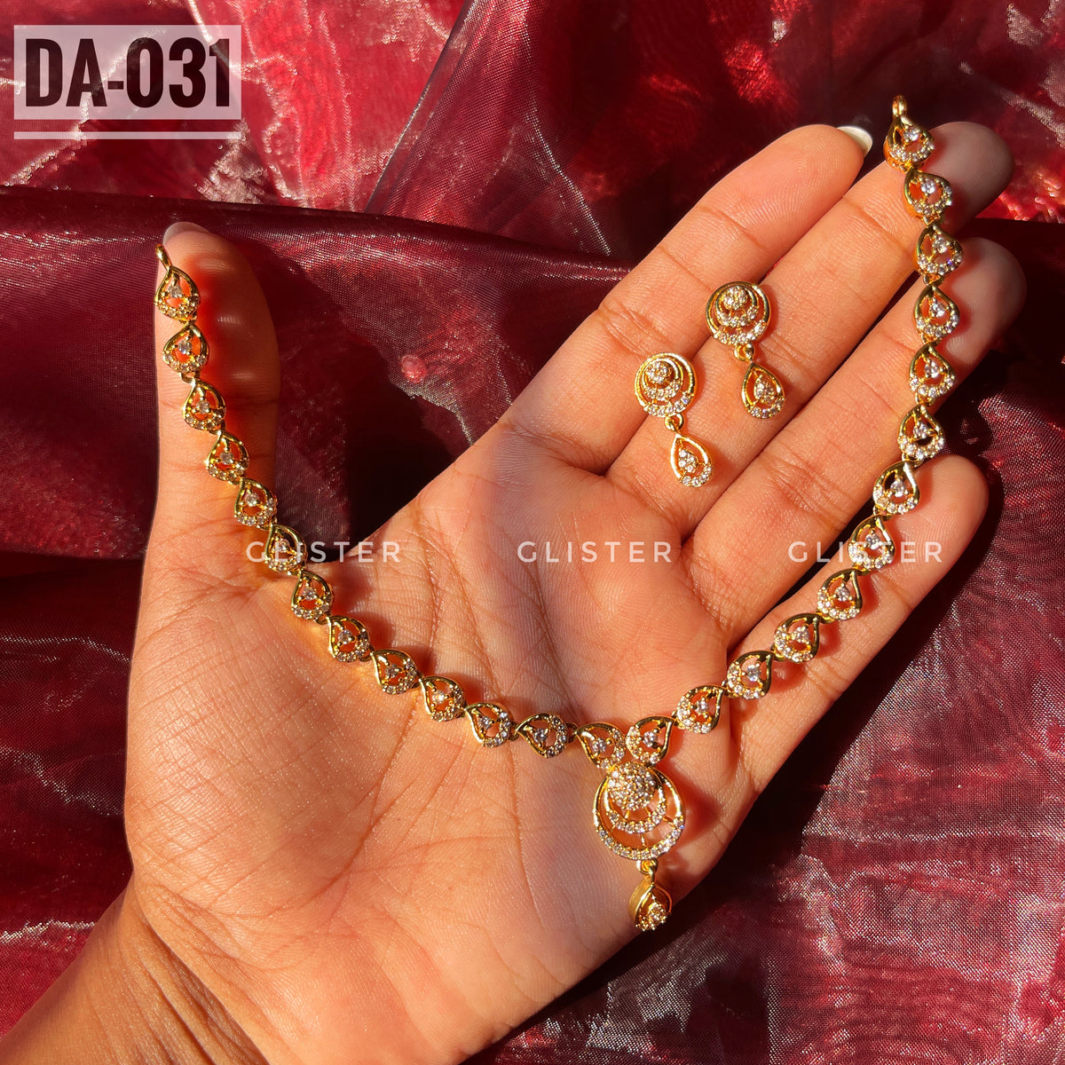 Gold-tone necklace with a teardrop pendant and matching earrings held in a hand