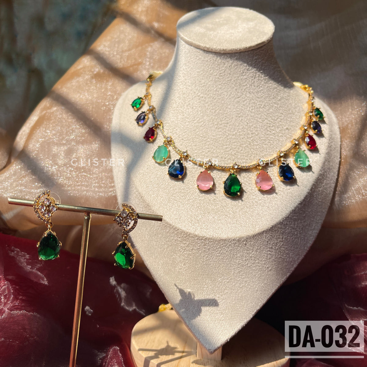 Gold-tone necklace with multicolor teardrop accents and matching green earrings on a display bust