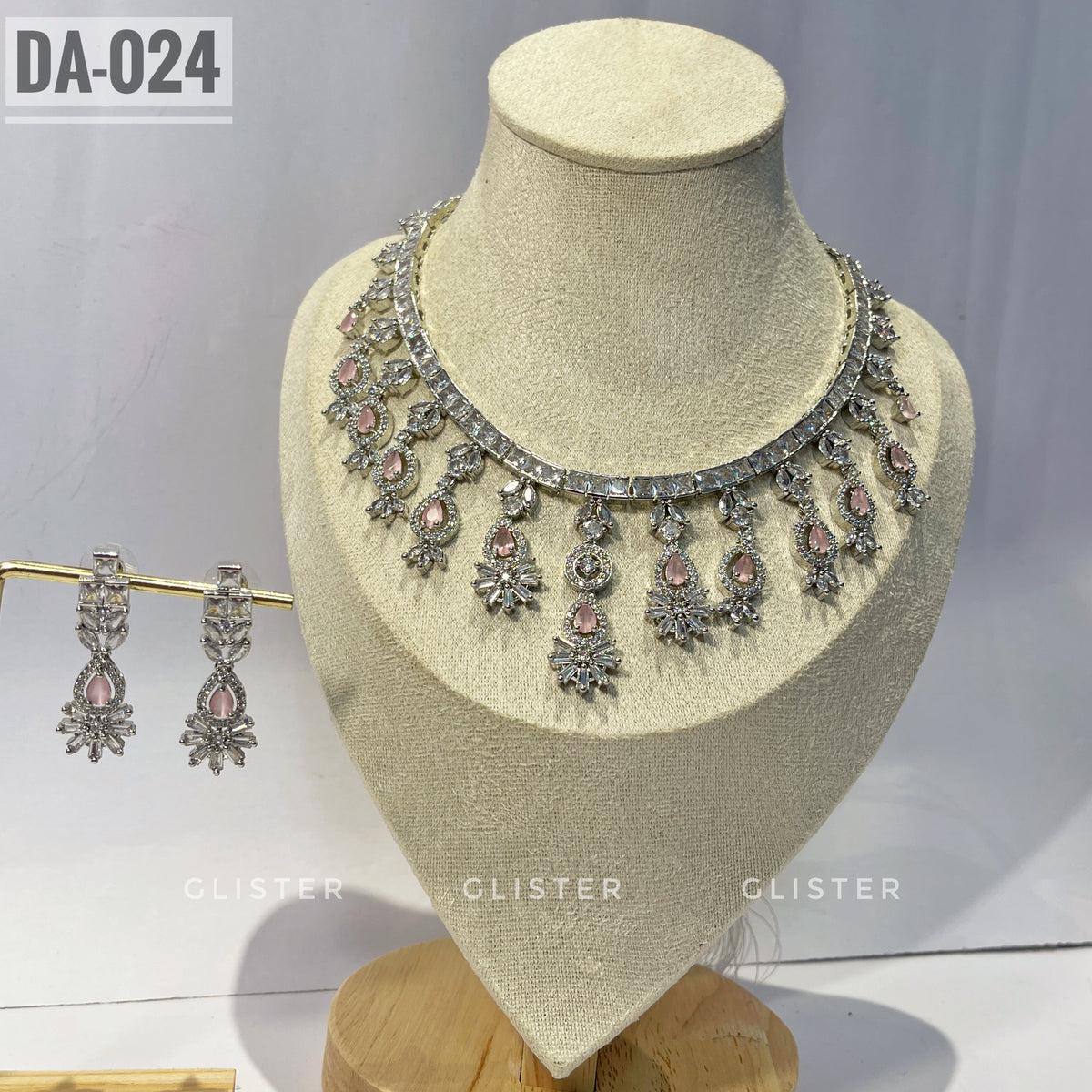 Silver-tone necklace and earrings with pink accents and a decorative fringe on a display bust
