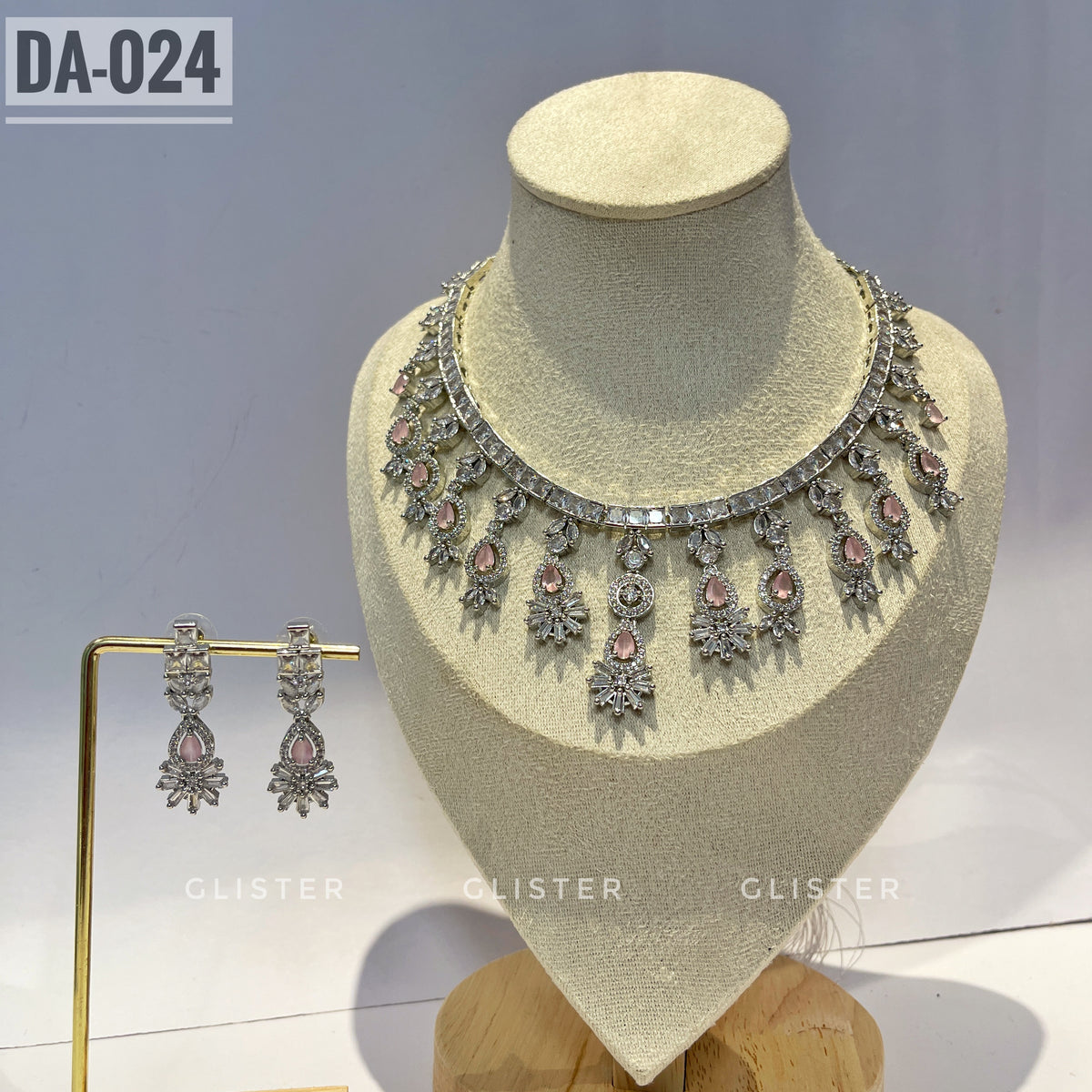 Silver-tone necklace and earrings with pink accents and a decorative fringe on a display bust