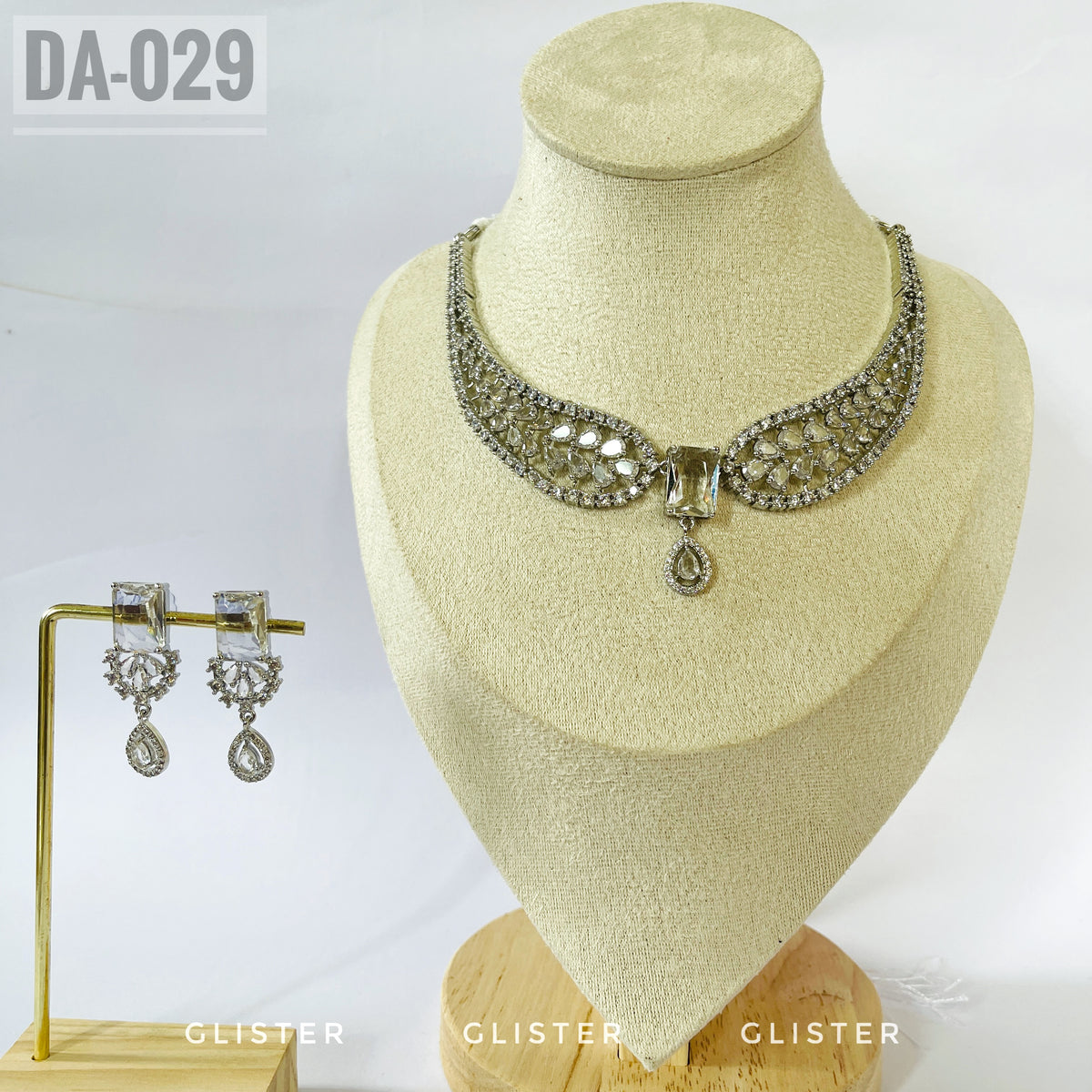 Silver-tone openwork necklace with a central drop and matching earrings on a display bust