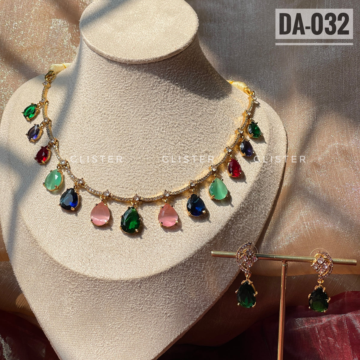 Gold-tone necklace with multicolor teardrop accents and matching green earrings on a display bust