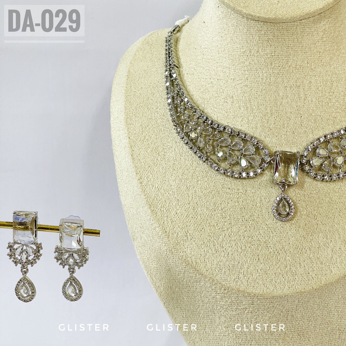 Silver-tone openwork necklace with a central drop and matching earrings close-up on a display bust