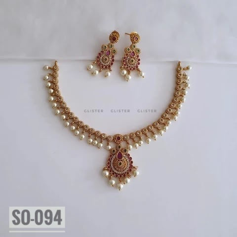 Gold-tone leaf necklace with a teardrop pendant and matching earrings on fabric