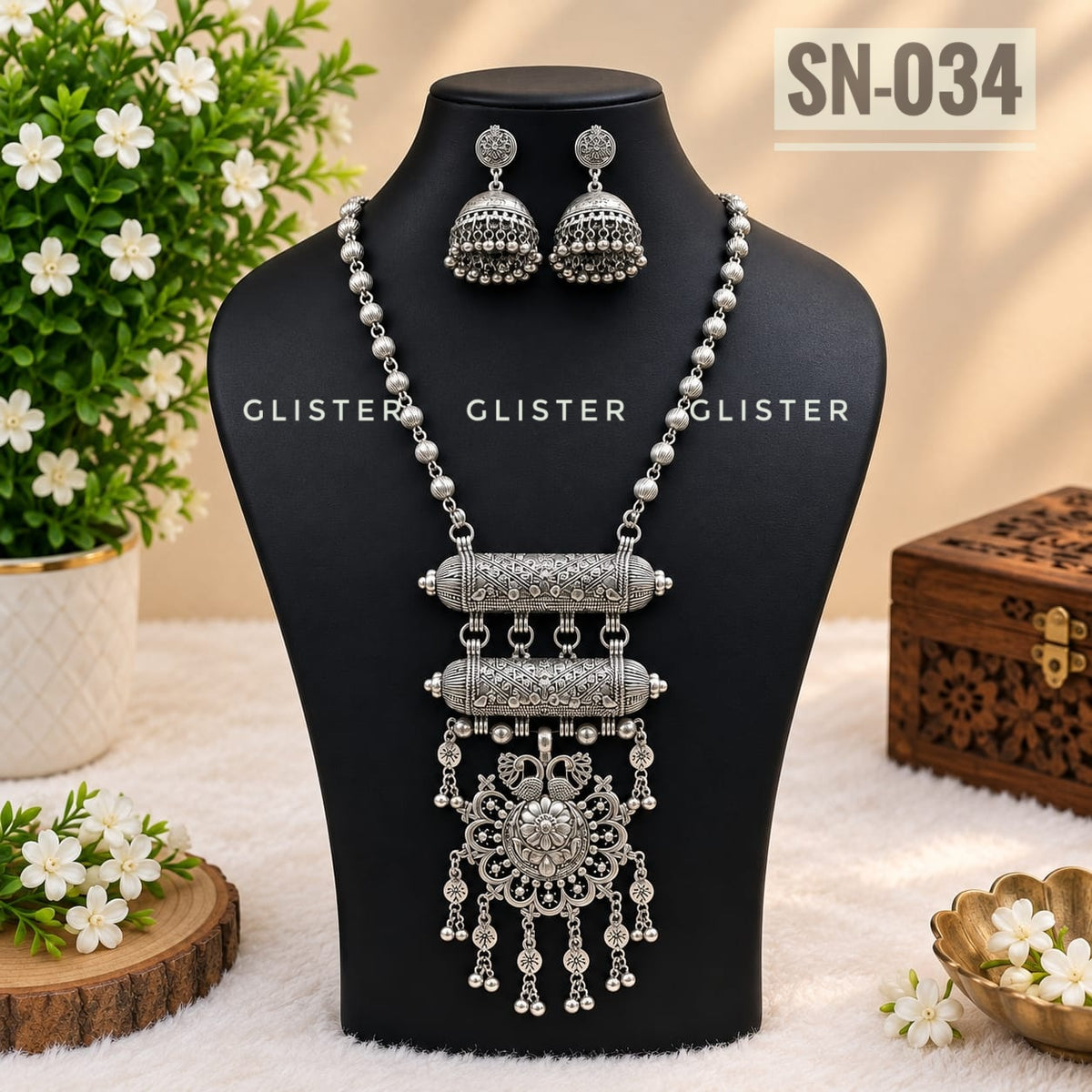 Silver-tone necklace with a chain fringe and matching jhumka earrings on a black bust