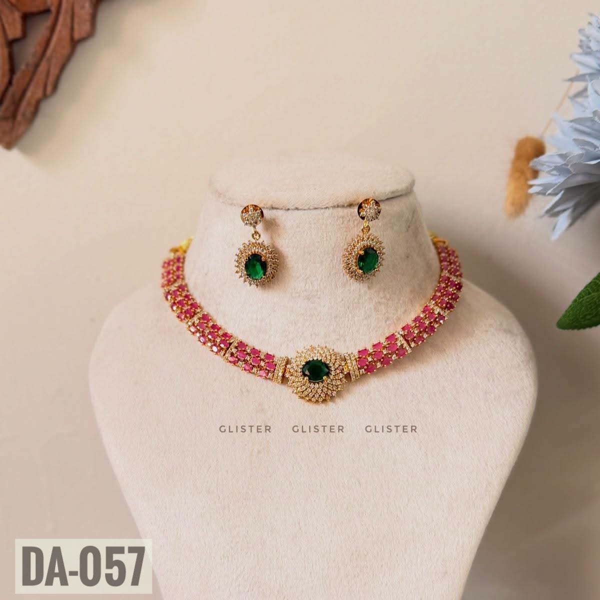 Glister DA-057: A necklace with rows of pink accents and a green oval floral centerpiece, paired with matching green drop earrings.