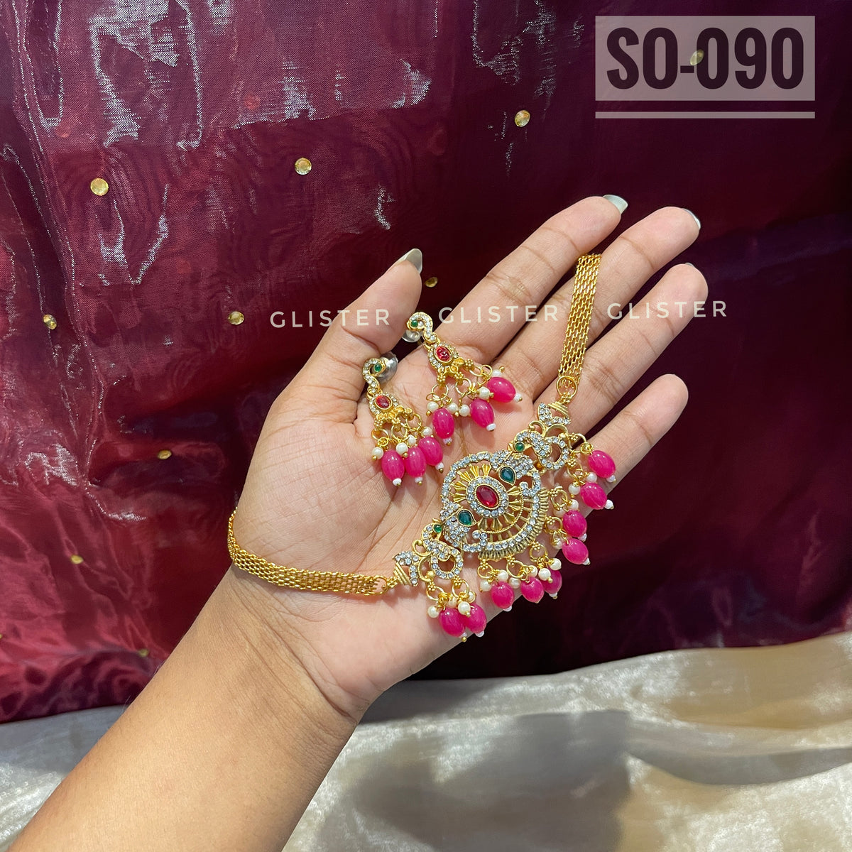 Gold-tone choker set with magenta bead drops held in a hand