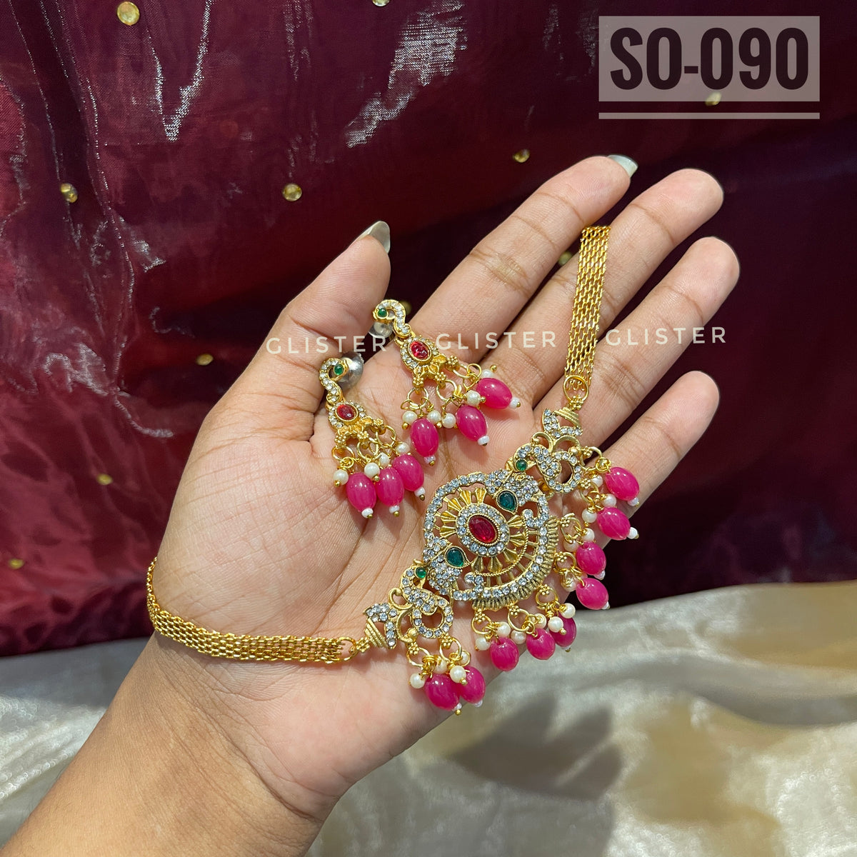 Gold-tone choker set with magenta bead drops held in a hand
