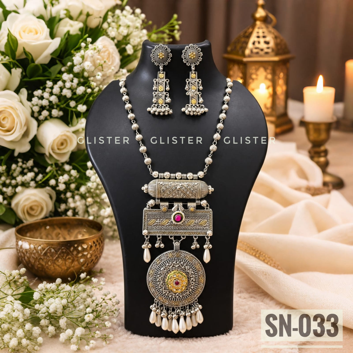 Silver-tone necklace with a round pendant, pink accents and matching earrings on a black bust