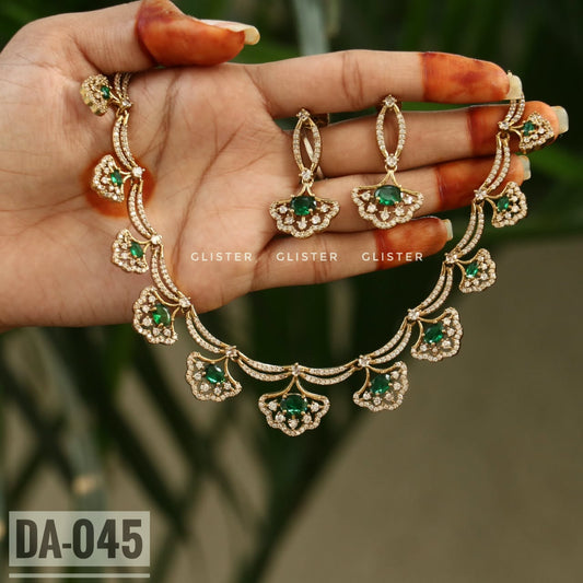 Gold-tone necklace with green floral drops and matching earrings held in a hand