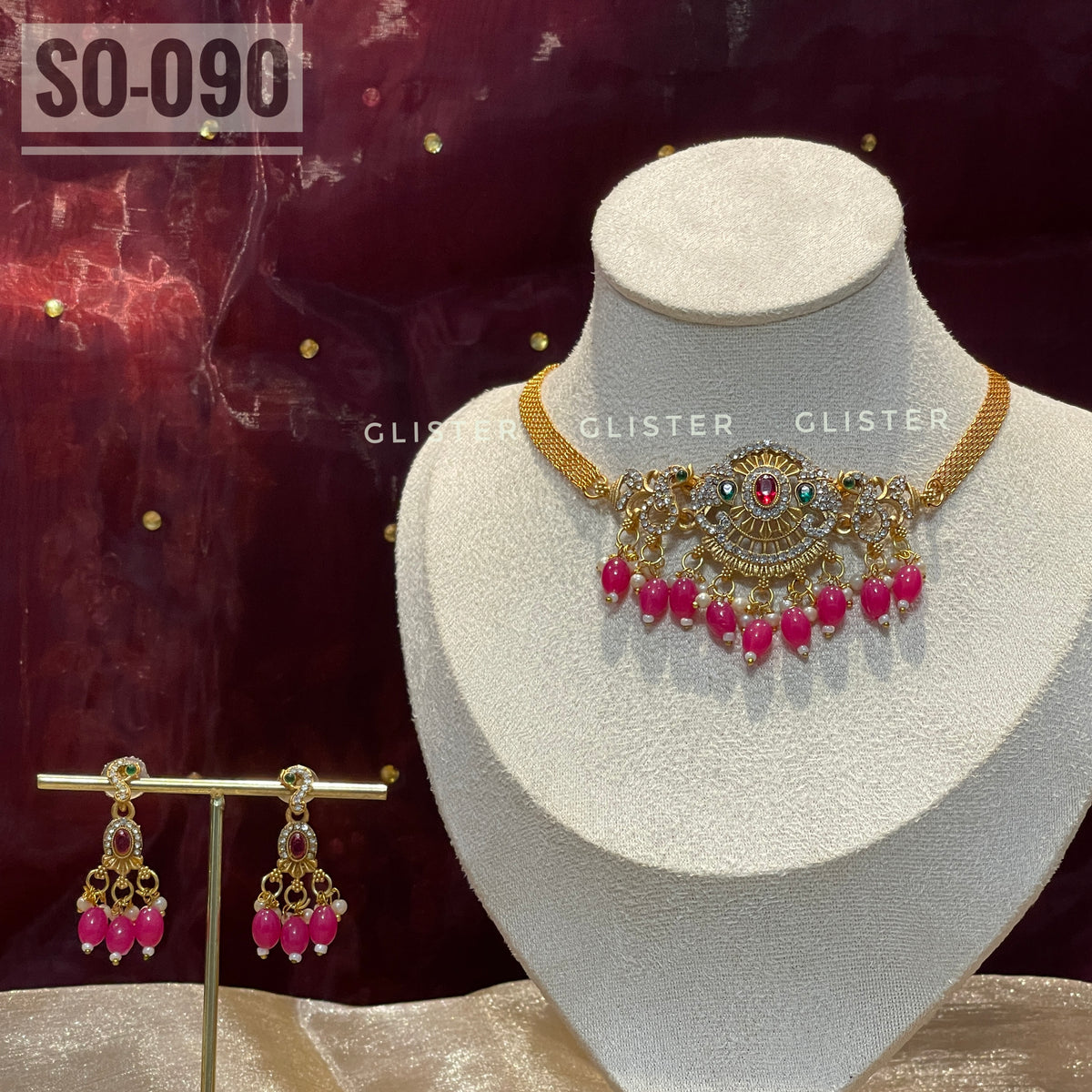 Gold-tone choker set with magenta bead drops on a display bust