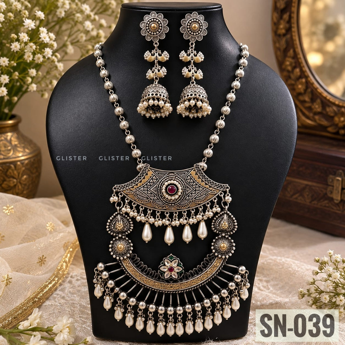 Glister SN-039: A long necklace with a layered crescent-shaped pendant, floral detailing and white hanging drops, paired with matching jhumka earrings.