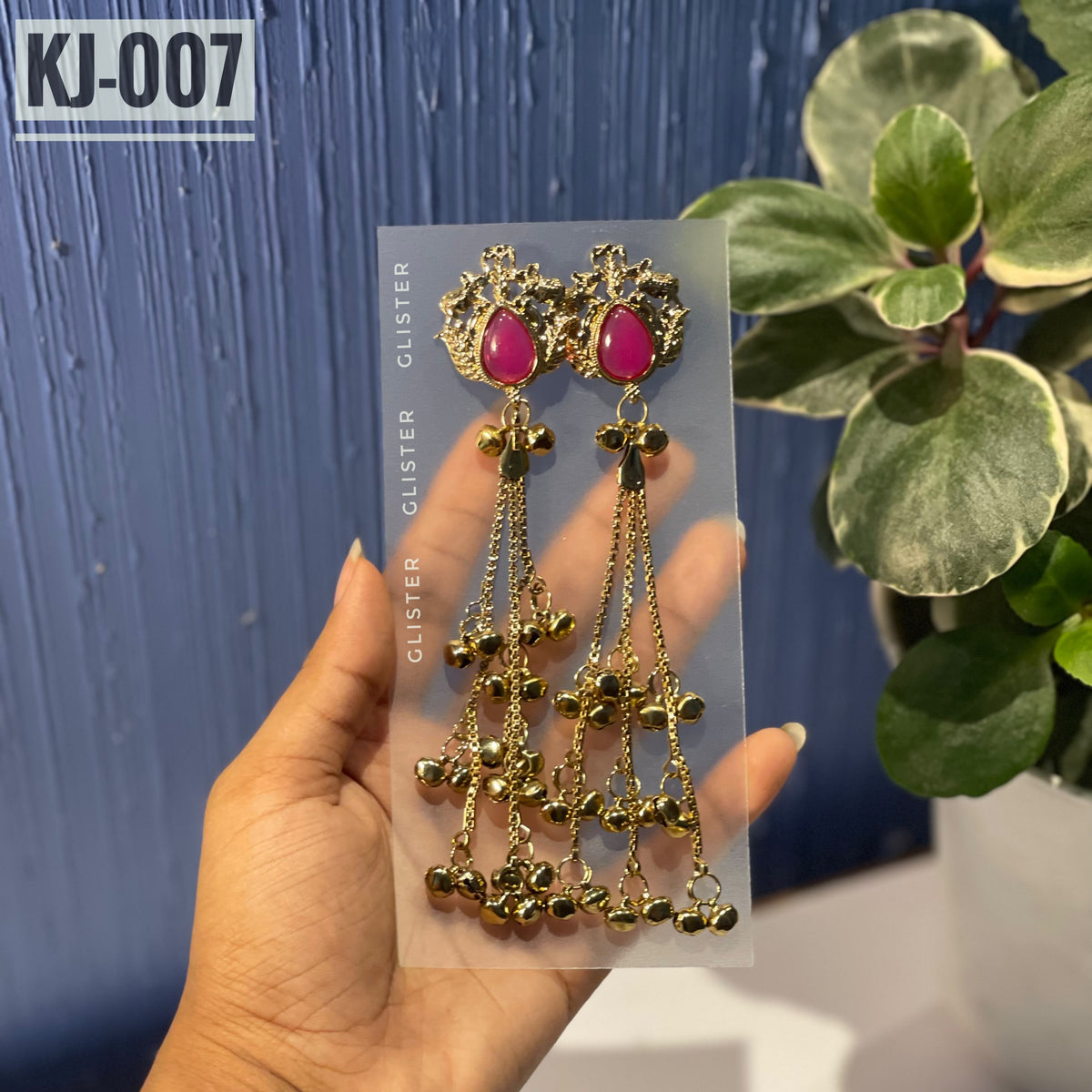 Glister KJ-007: A pair of Kashmiri-inspired long earrings with ornate tops and teardrop-shaped colored accents, hanging chains and clusters of small bell-like drops, close-up held in hand.