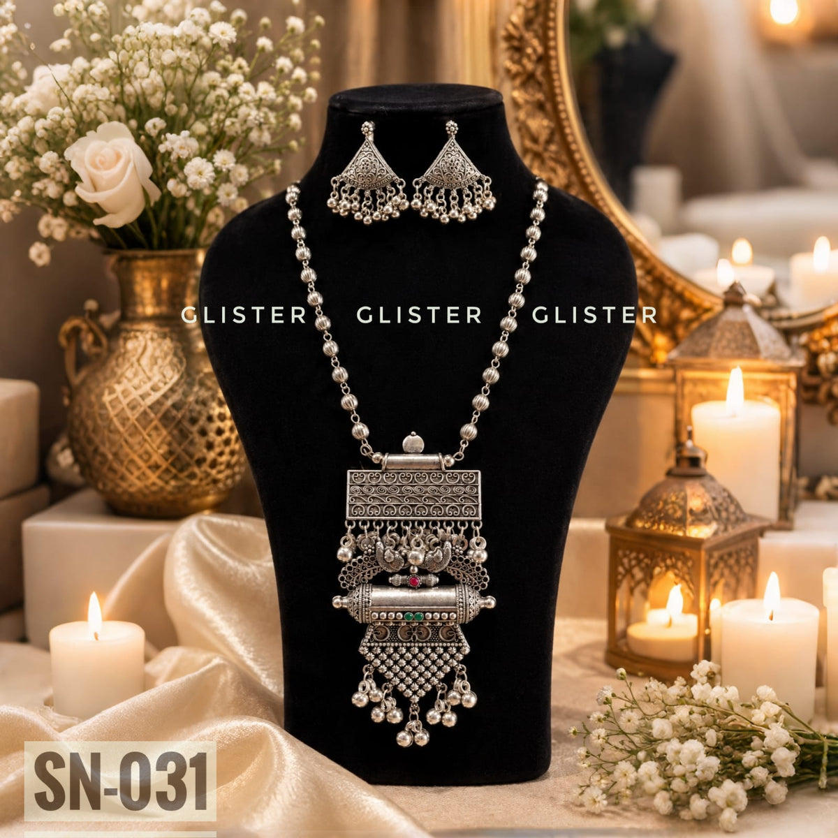 Silver-tone beaded necklace with a tiered pendant and triangular earrings on a black bust