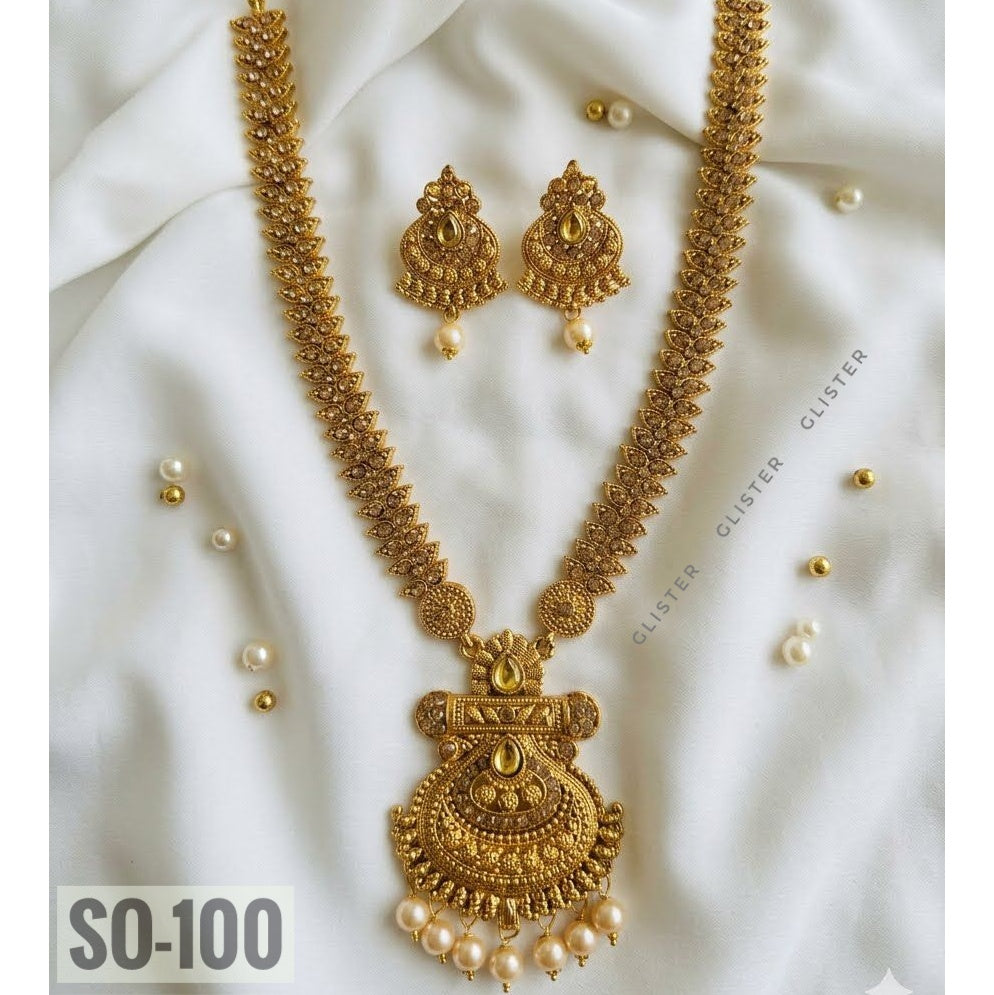 Gold-tone long necklace with a fan-shaped pendant, white bead fringe and matching earrings on fabric