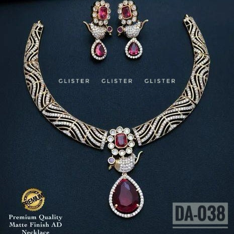 Gold-tone patterned necklace with a dark-purple teardrop pendant and matching earrings on a dark background