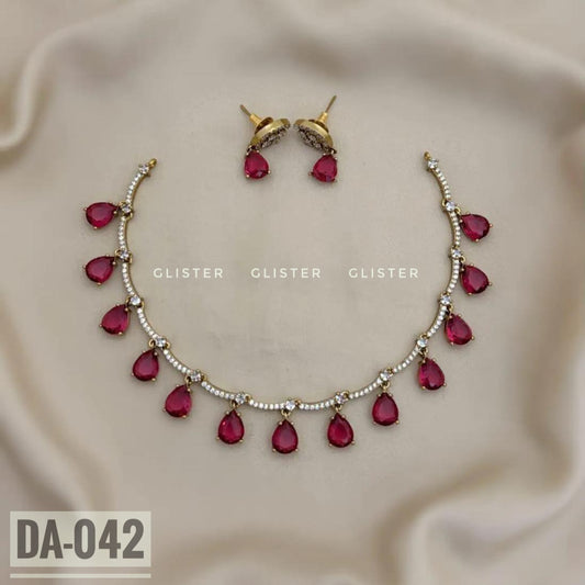 Silver-tone necklace with magenta teardrop accents and matching earrings on pale fabric
