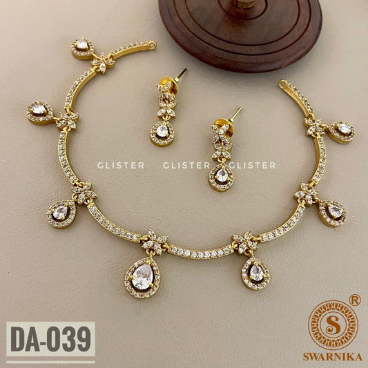 Gold-tone necklace with clear teardrop accents and matching earrings on pale fabric