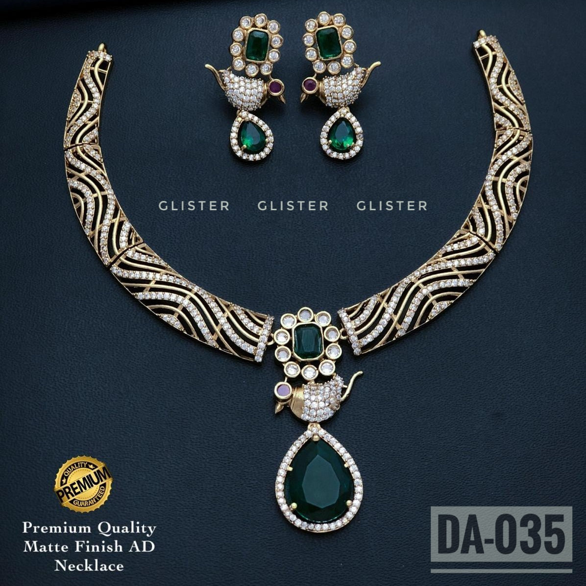 Gold-tone patterned necklace with a green teardrop pendant and matching earrings on a dark background