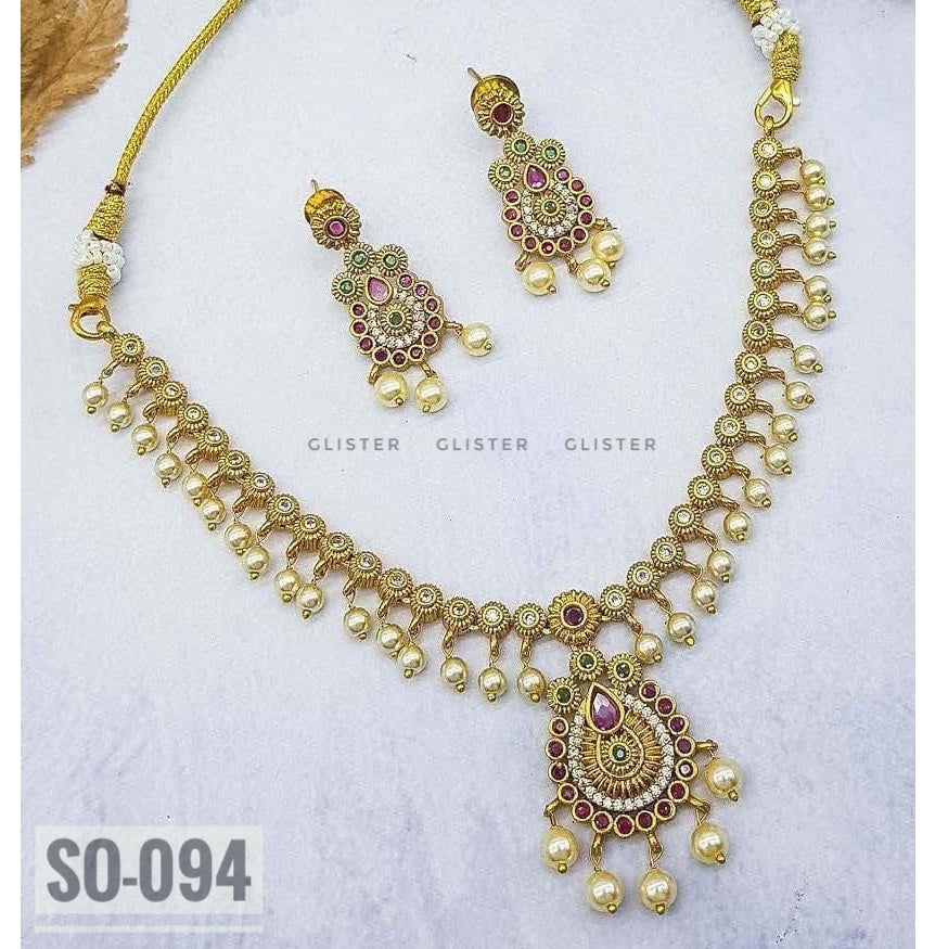 Gold-tone leaf necklace with a teardrop pendant and matching earrings on fabric