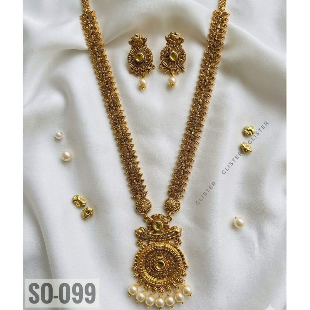 Gold-tone long necklace with a circular pendant, white bead drops and matching earrings on fabric