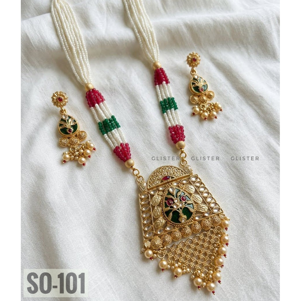 Red, green and white beaded necklace with a gold-tone rectangular pendant and matching earrings on fabric