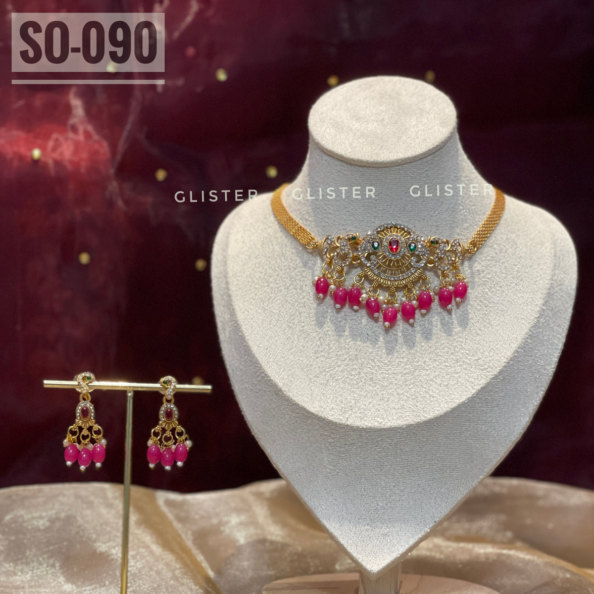 Gold-tone choker set with magenta bead drops on a display bust