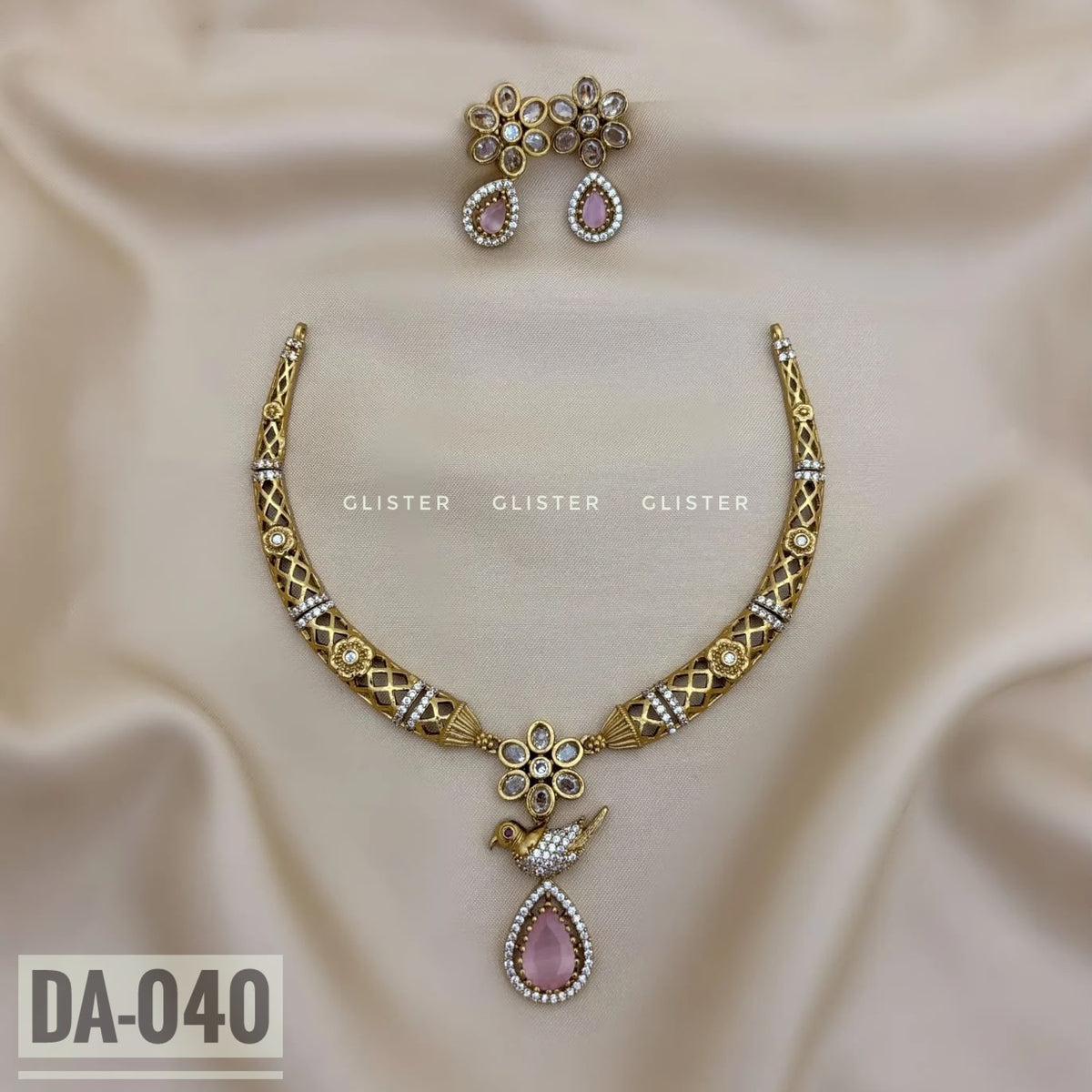 Gold-tone curved necklace with a lavender pendant and matching earrings on pale fabric
